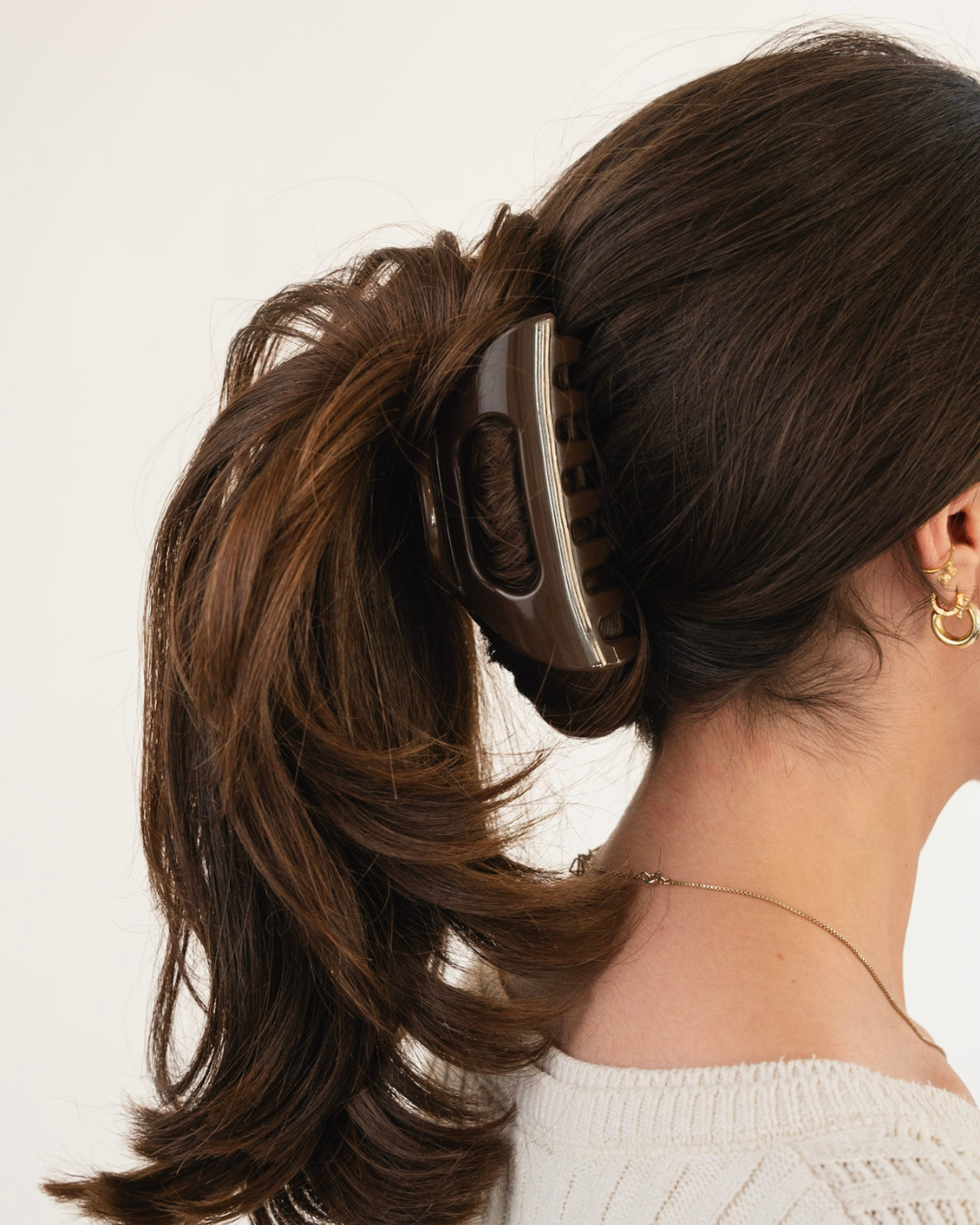 Brown claw hair clip holding a woman's dark brown ponytail, shown from the back.