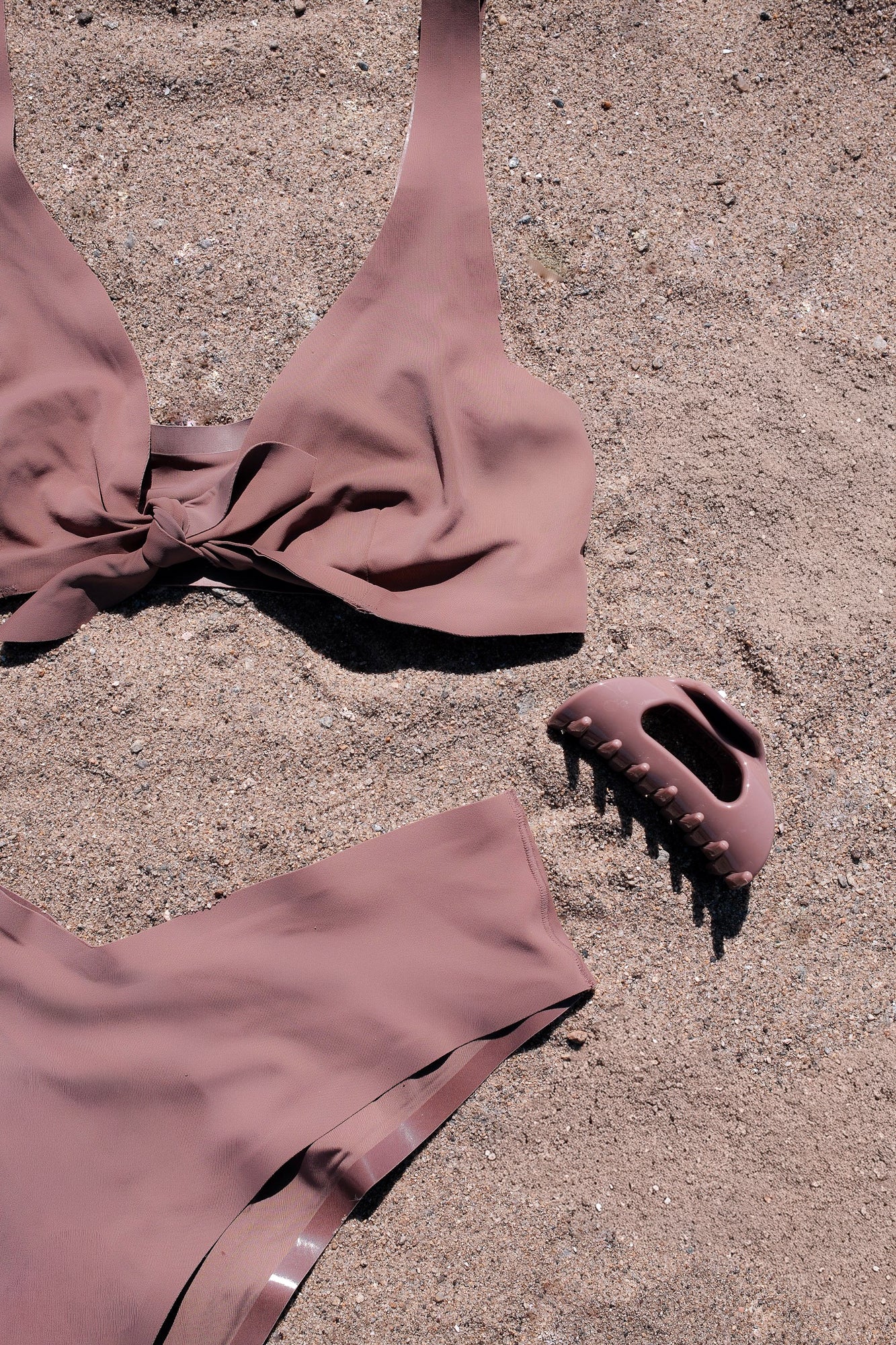 Top-down view of Cozy Clip x onewith Duo bikini and matching flexible claw clip showcasing Cove taupe color on sand
