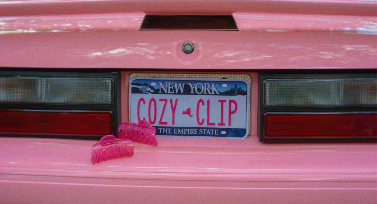Two pink glittery flexible claw clips displayed in a pink car with a New York Cozy Clip license plate