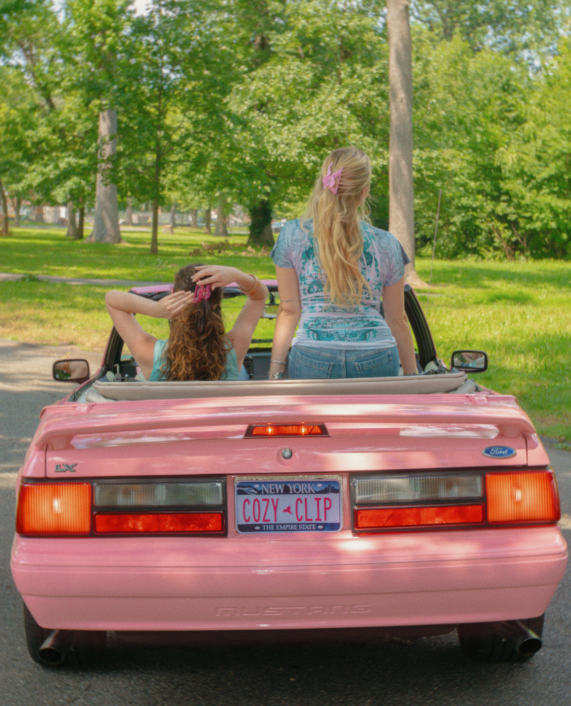 Two women style pink pixie dust flexible cozy claw clips in a pink convertible in a sunny park