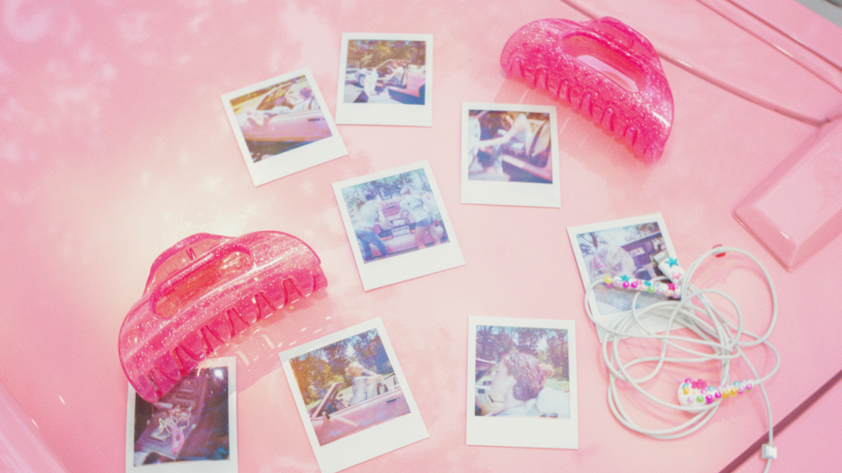 Pixie Dust pink Cozy flexible claw clips displayed with instant photos and beaded earphones on a pink surface