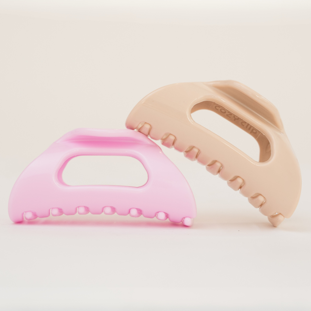 Front view of two Cozy Clip hair clips, blonde and baby pink, showing flexible rounded teeth on a pale background