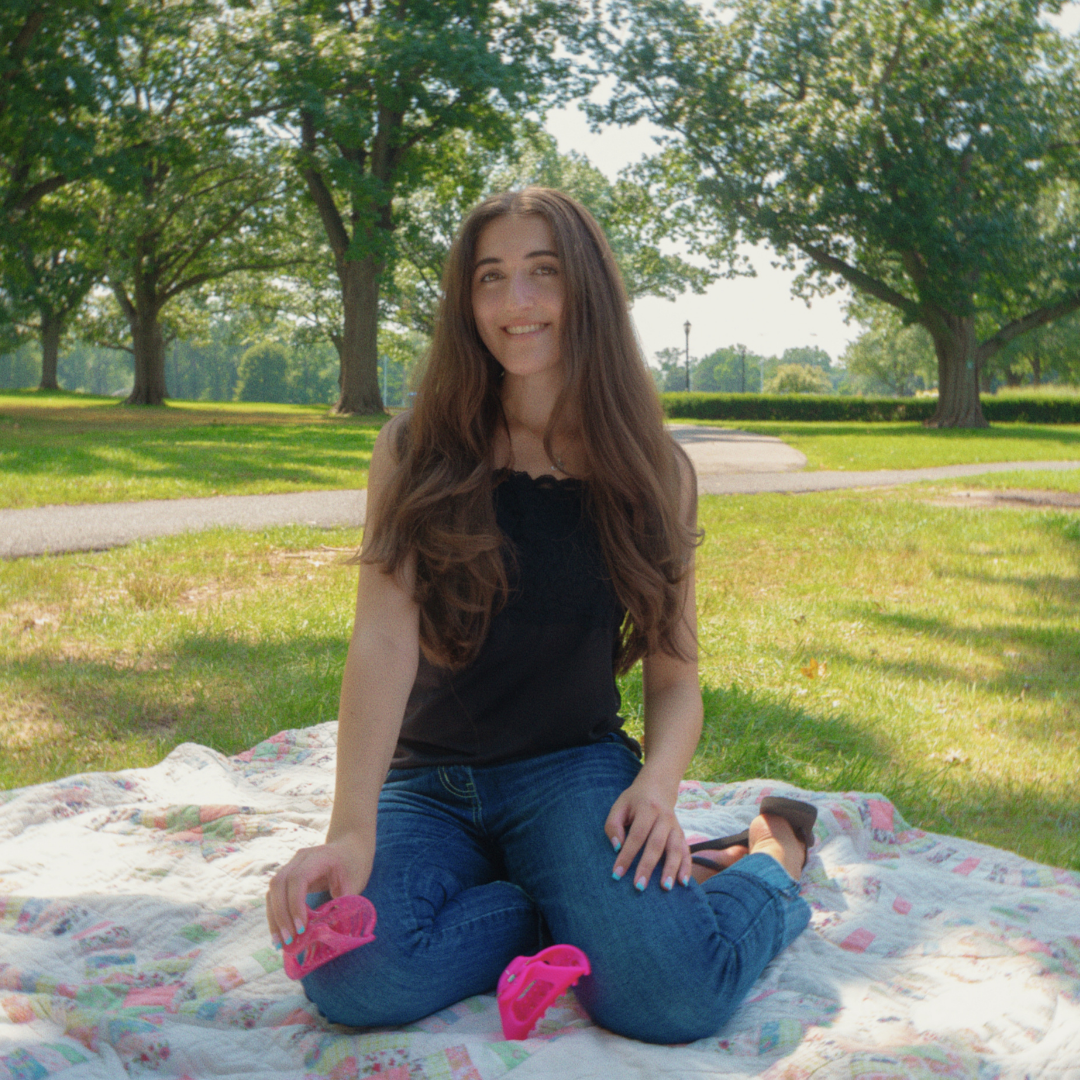 Woman displays Pixie Dust Cozy Clip and 3D printed Cozy Clip while sitting on a picnic blanket outdoors